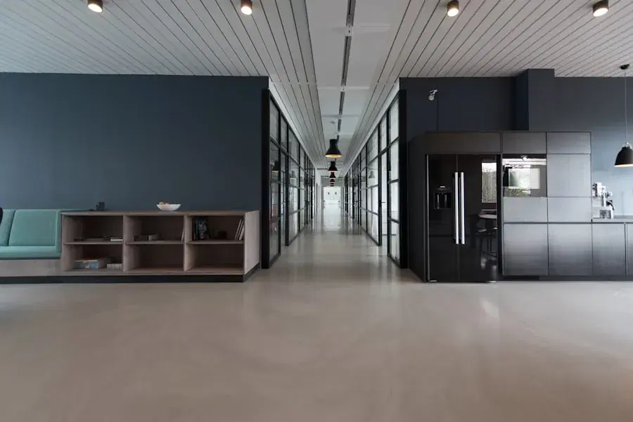 Open office corridor with glass-walled rooms and a kitchen area