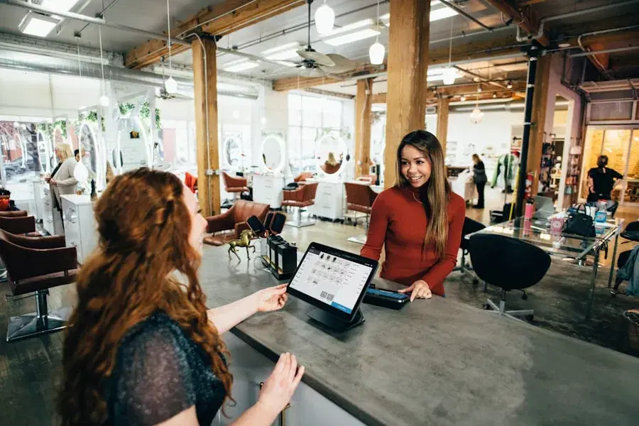 Receptionist booking a customer in on a tablet at a salon